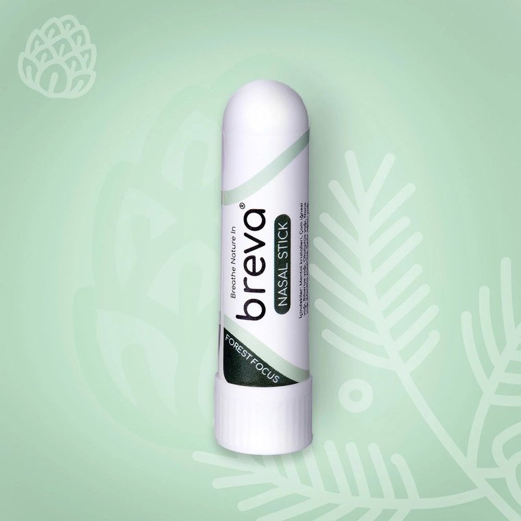 Forest Focus Nasal Stick, adaçayı yeşili bir zeminde çam iğnesi çizimleri arasında duruyor.