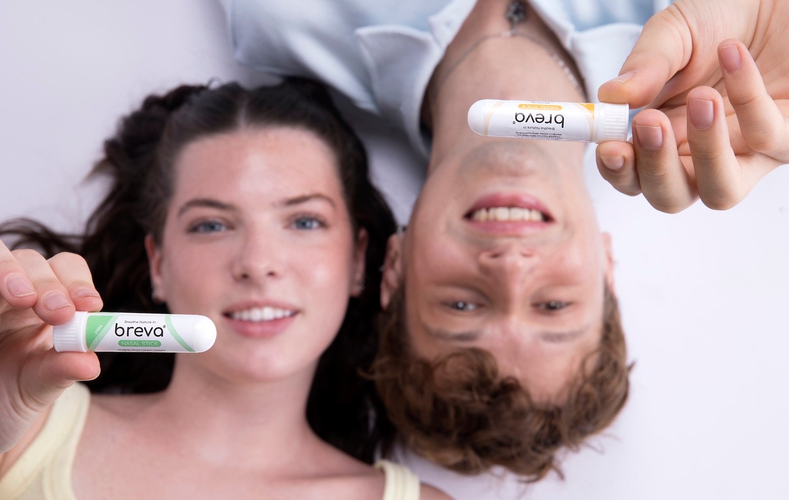 Breva Nasal Stick'in Mint ve Tropical aromalarını elinde tutan iki kişi